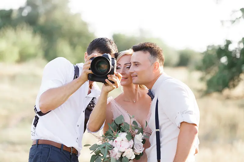 Image of a photographer showing photos taken to a wedding couple
