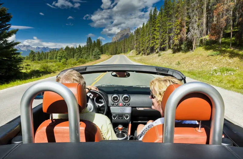 Couple in a convertible driving through Banff National Park