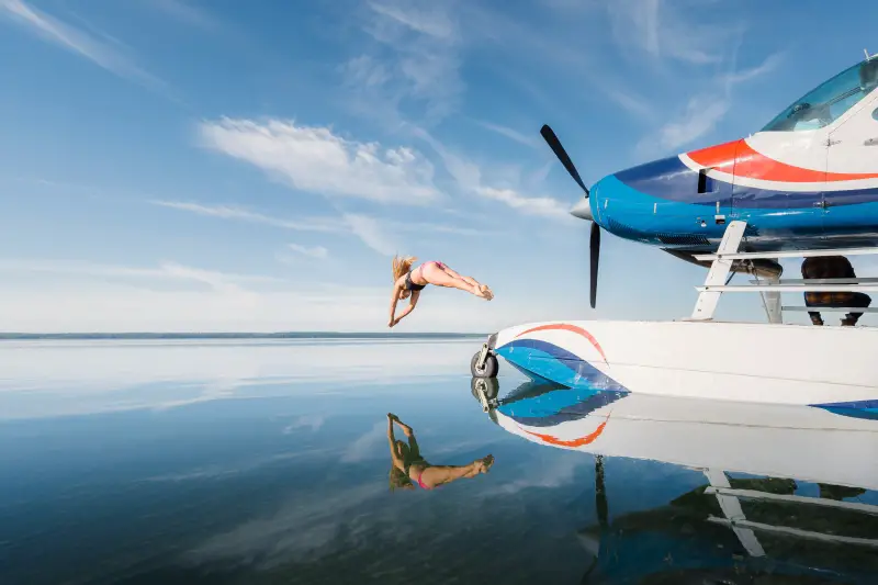 Women diving off of float plane