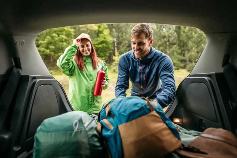 couple packing camping equipment in the car trunk